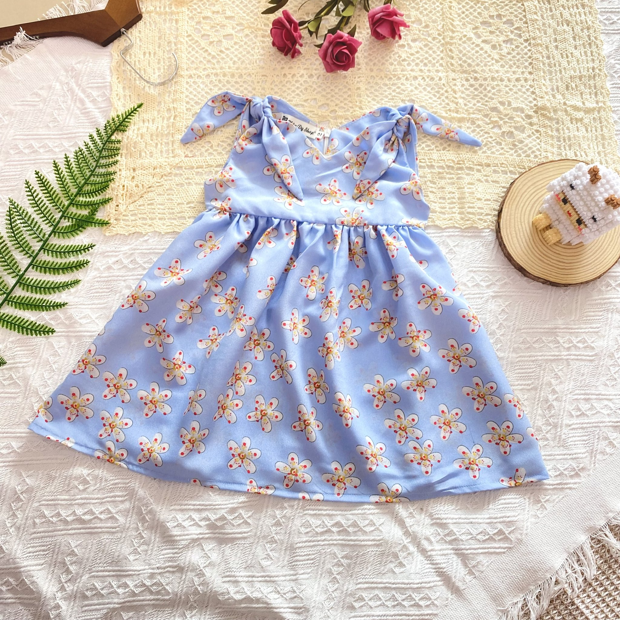 Đầm hoa nhí sát nách đính nơ cổ tim xinh cho bé