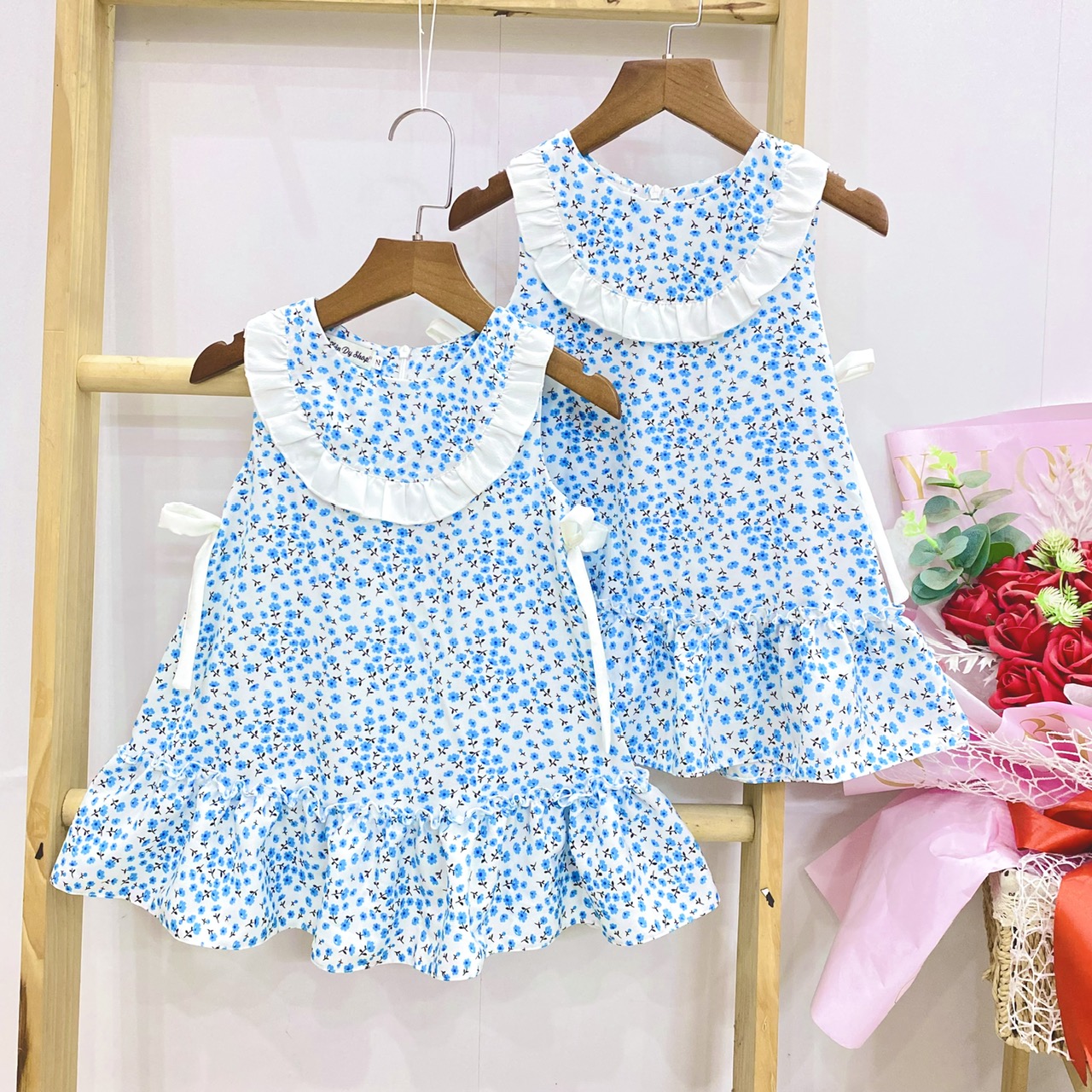 Đầm cổ tròn đính nơ hoạ tiết hoa nhí đáng yêu cho bé
