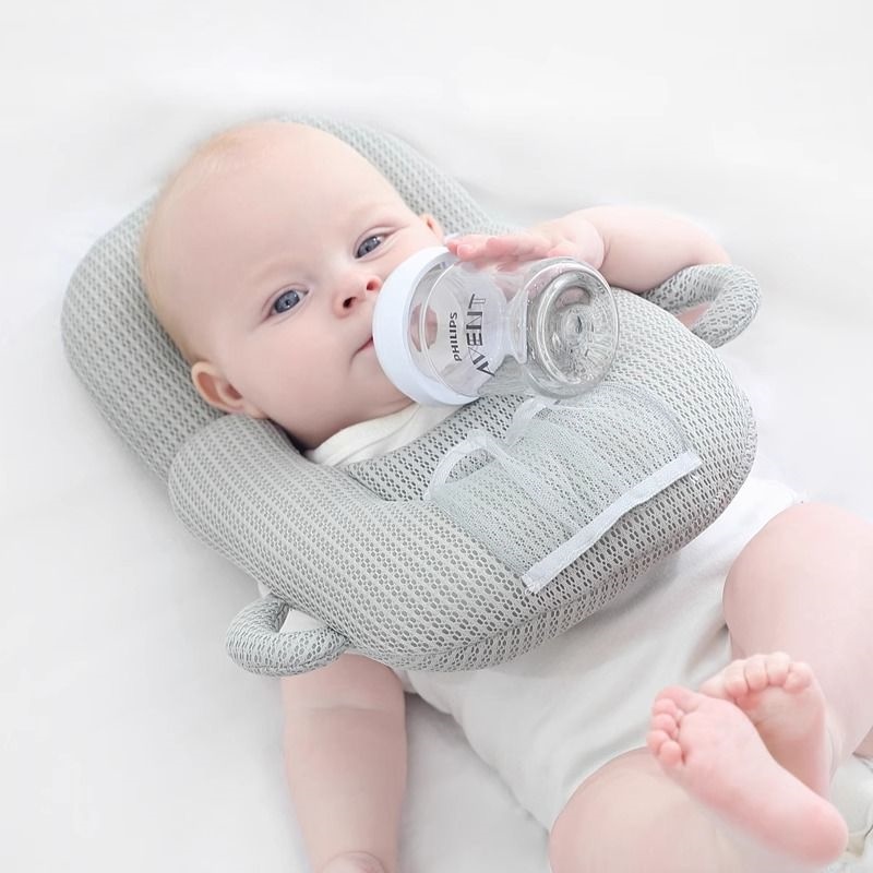 Người lười biếng cho con bú và cho bé sơ sinh nằm trên giường và bú bình sữa khung cố định gối cho bé
