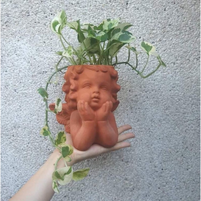 Chậu đất nung hình thiên thần chống cằm.